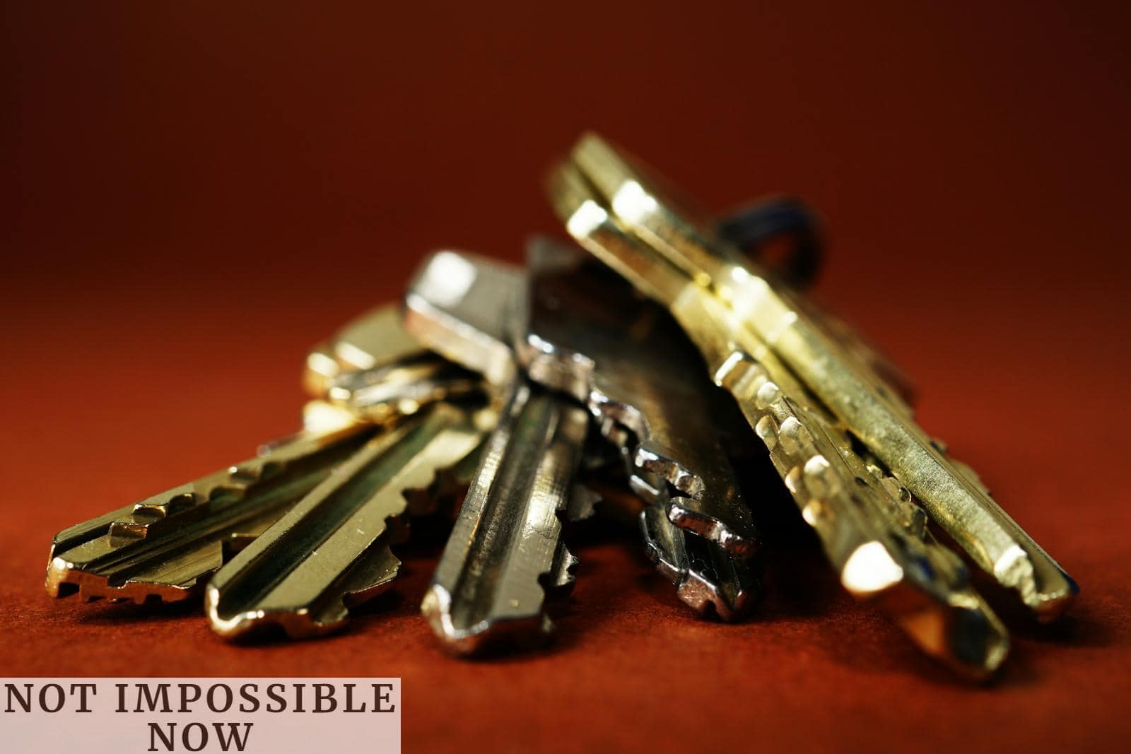 Detailed view of a pile of metallic keys on a deep red surface, emphasizing security and safety.
