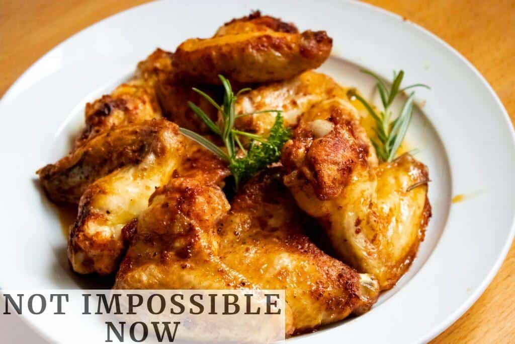 Golden-brown chicken wings garnished with fresh herbs, perfect for a tasty meal.