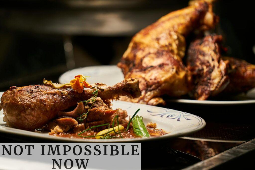 Close-up of a deliciously roasted chicken dish served with garnish, highlighting fine cuisine.