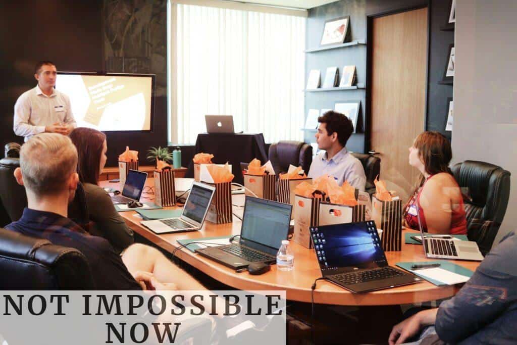 man standing in front of people sitting beside table with laptop computers